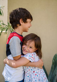 Siblings hugging  against wall