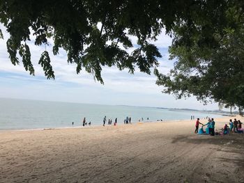 People at beach against sky