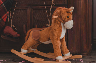 Soft children's rocking horse on the background of an old chest of drawers