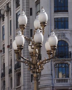 Low angle view of old-fashioned street light against building in city