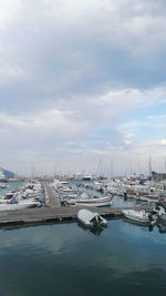 Boats moored at harbor against sky