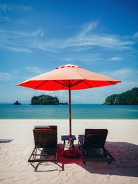 Deck chairs on beach against sky