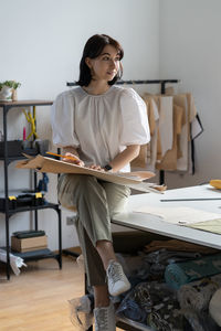 Full length of young woman sitting on table