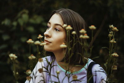 Young woman looking away against plants