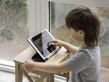 Curious boy watch cartoons on digital tablet. kid uses electronic device. indoor leisure 