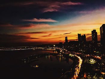 Illuminated cityscape against sky at sunset