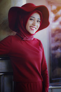 Portrait of smiling young woman wearing hijab and red hat