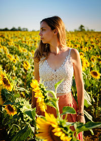 Young woman standing amidst yellow flowers