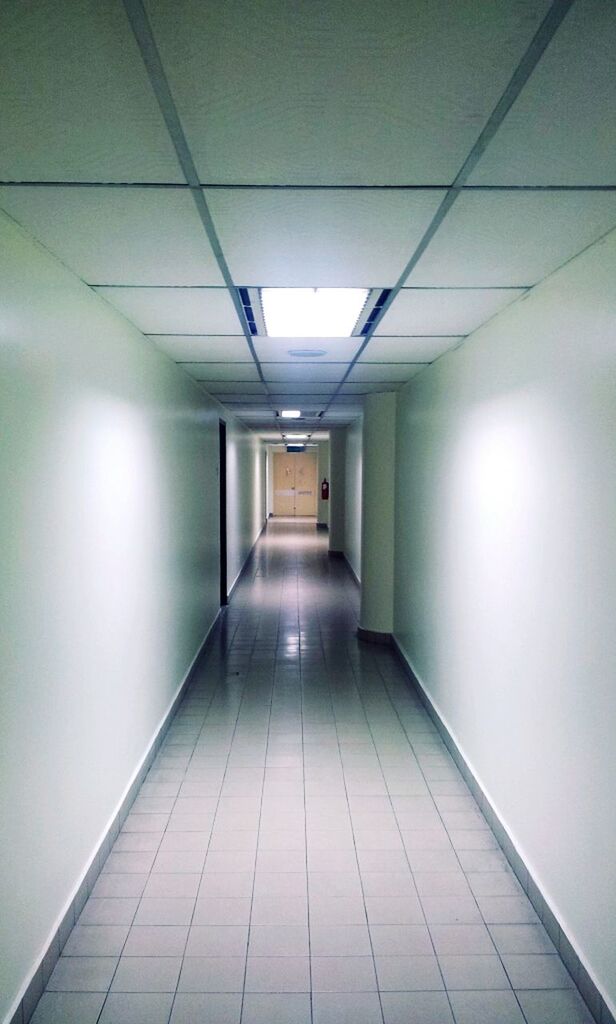 indoors, the way forward, architecture, corridor, built structure, ceiling, illuminated, diminishing perspective, empty, vanishing point, lighting equipment, wall - building feature, modern, tiled floor, building, absence, flooring, narrow, wall, long