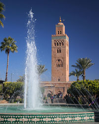 View of fountain with clock tower against sky