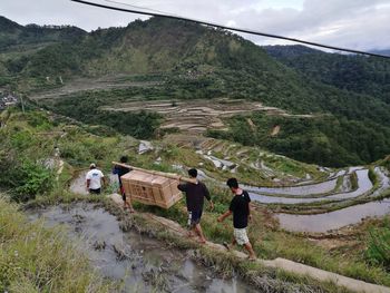 Rear view of people walking on mountain against sky