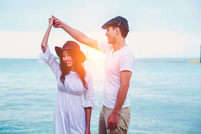 Young couple standing in sea against sky