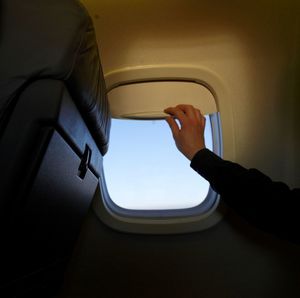 Man closing airplane window