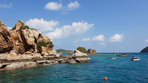 Scenic view of rocks by sea against sky