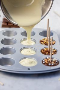Close-up of bowl pouring melted white chocolate in baking sheet on table