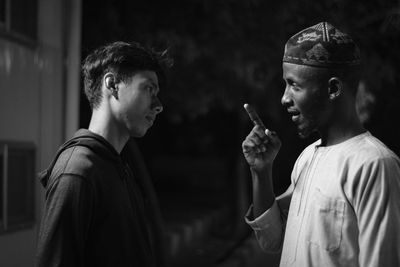 Side view of young men talking while standing outdoors