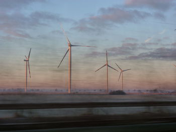 Windmills against sky at sunset