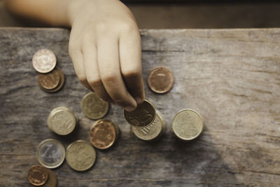 Close-up of hand holding coins on table