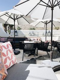 Empty chairs and tables at restaurant against sky