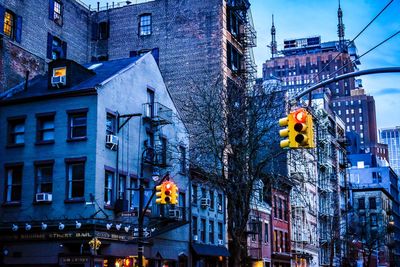 Illuminated street light against buildings in city