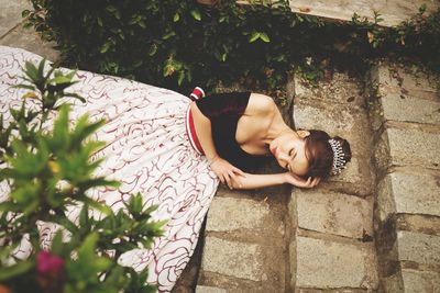 High angle view of beautiful woman wearing gown and tiara while lying on steps