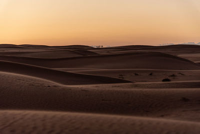 Scenic view of desert against clear sky during sunset