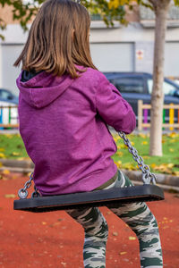 Rear view of girl swinging in playground