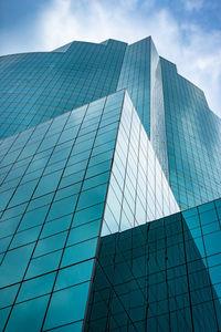 Low angle view of modern glass building against sky