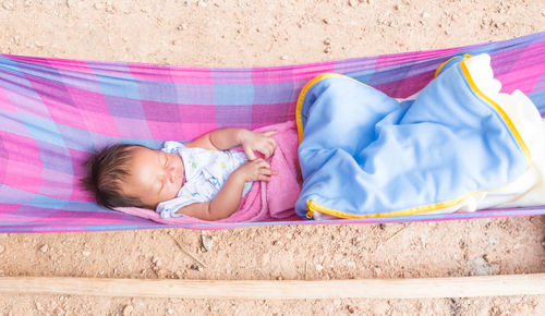 High angle view of cute baby girl sleeping in hammock outdoors