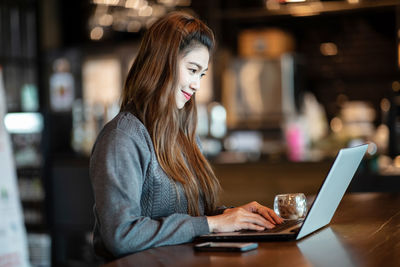 Woman using laptop while sitting at table in cafe