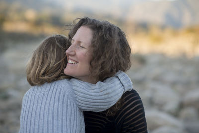 Mother embracing daughter laughing outdoors