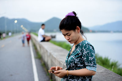 Beautiful happy woman using phone by lake