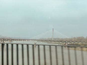 Bridge over river against sky in city