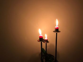 Close-up of illuminated candle against wall