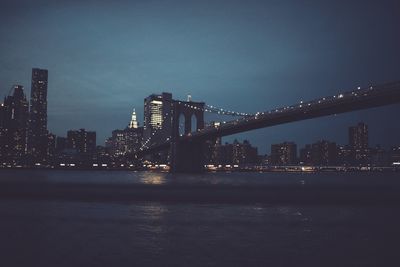 Illuminated bridge over river at night