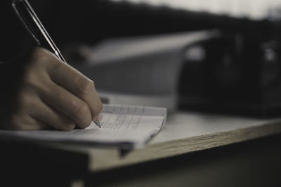 Cropped hand of businessman working on table