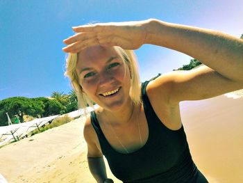 Portrait of smiling young woman on beach against clear sky