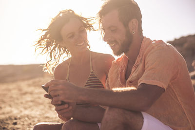 Young couple on beach against sky