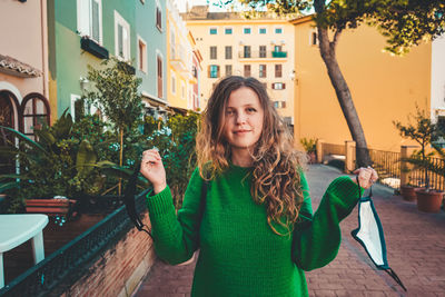 Portrait of smiling woman standing against plants in city