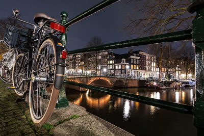 Bicycles on bridge over river in city at night