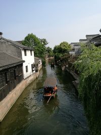 Boats in canal amidst buildings against clear sky