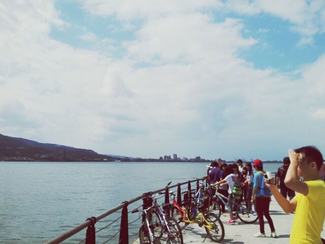 water, lifestyles, sky, leisure activity, railing, men, transportation, sea, large group of people, mode of transport, cloud - sky, nautical vessel, person, river, bicycle, day, travel, nature, built structure