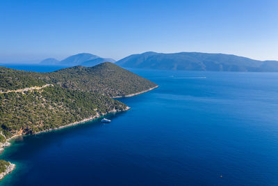 Scenic view of sea and mountains against clear blue sky