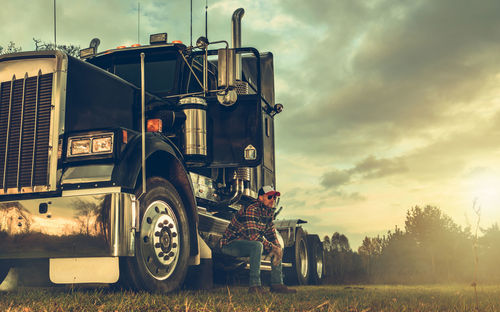 Truck on field against sky during sunset