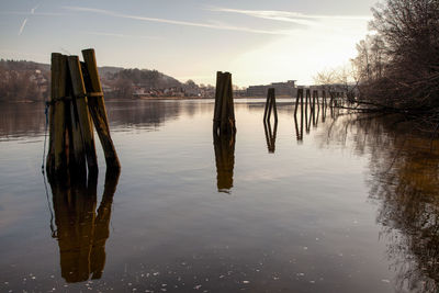 Wooden posts in lake against sky