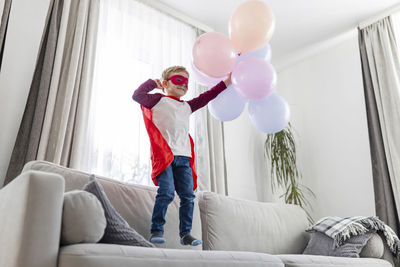 Young woman with balloons while sitting on bed at home