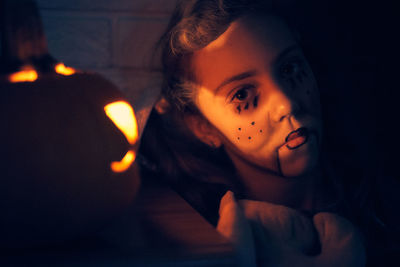 Cute girl wearing costume standing by pumpkin during halloween