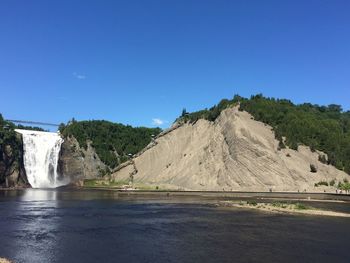 Scenic view of waterfall against clear blue sky