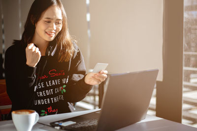 Young woman using laptop on table at home