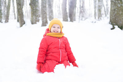 Portrait of smiling boy standing on snow covered field